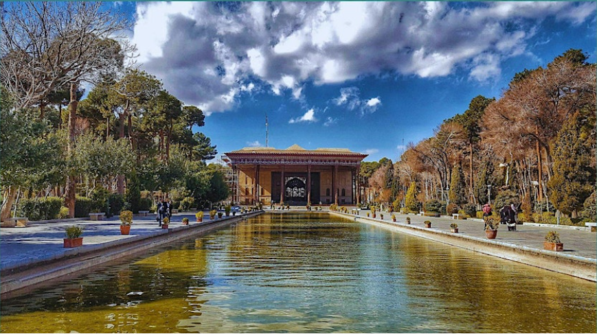 man-made pond in middle of curated garden with trees and structure