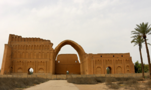 old building with large arch, palm trees on right