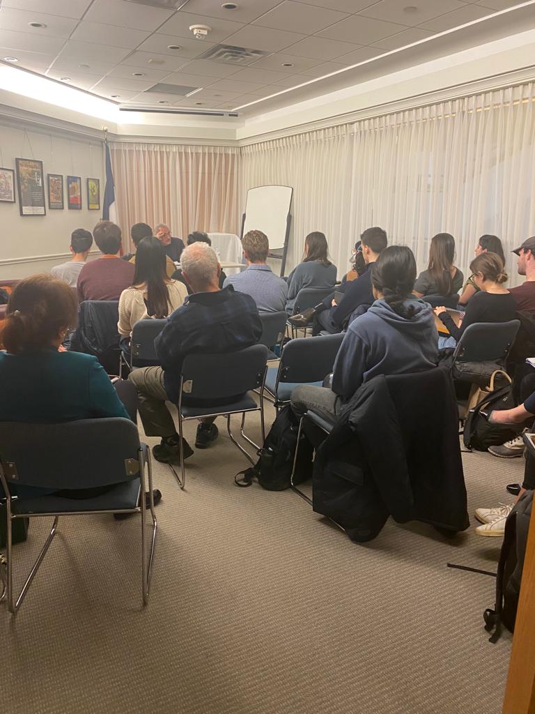 people sitting in room facing Abbas Milani