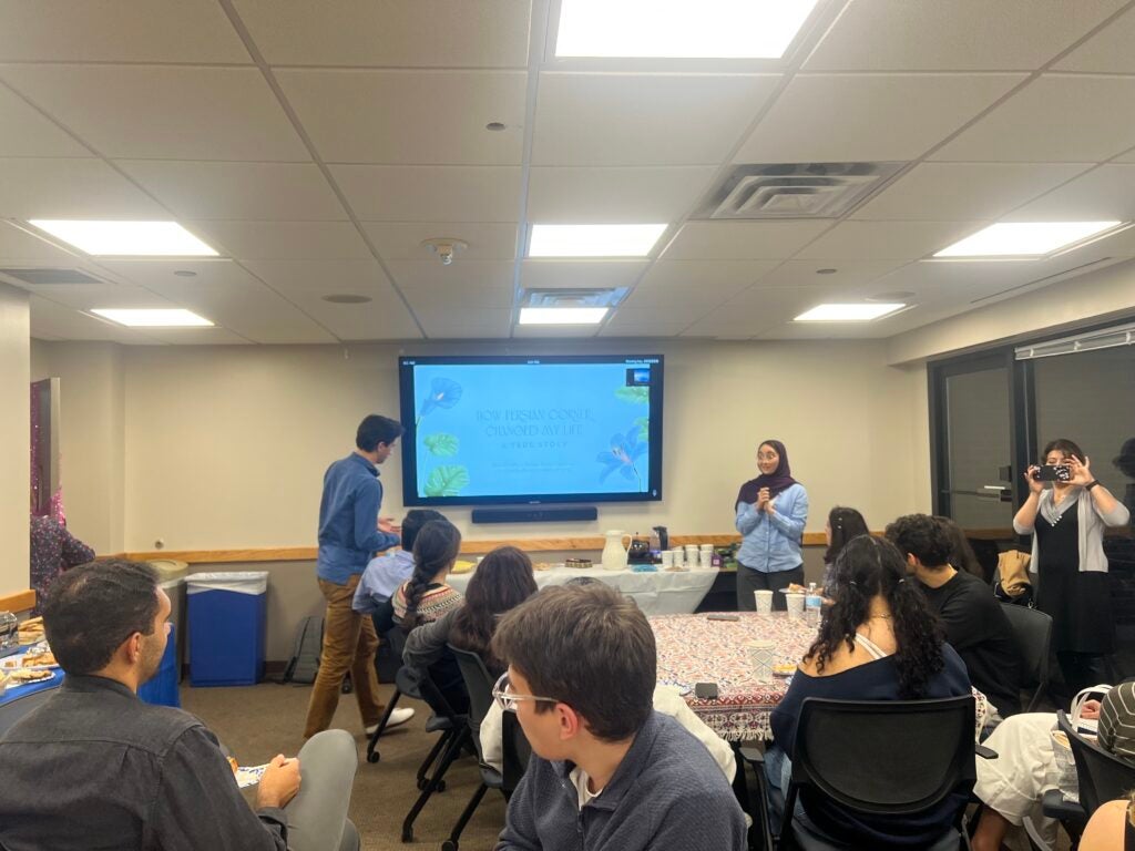 people sitting at tables watching presentation on screen